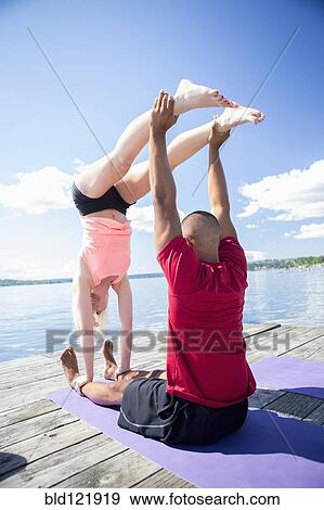 Caucasian couple practicing acroyoga on wooden dock View Large Photo Image Stock Photo - Caucasian couple practicing acroyoga on wooden dock. Fotosearch