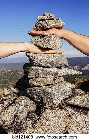 Stock Photo - Caucasian couple stacking their hands in rocks. Fotosearch