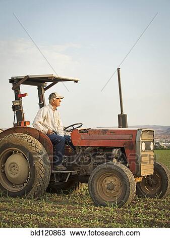 Caucasian farmer driving tractor in crop field View Large Photo Image Stock Image - Caucasian farmer driving tractor in crop field. Fotosearch