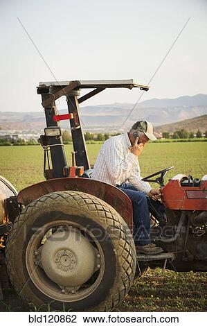 Caucasian farmer using cell phone on tractor in crop field View Large Photo Image Stock Image - Caucasian farmer using cell phone on tractor in crop field. Fotosearch