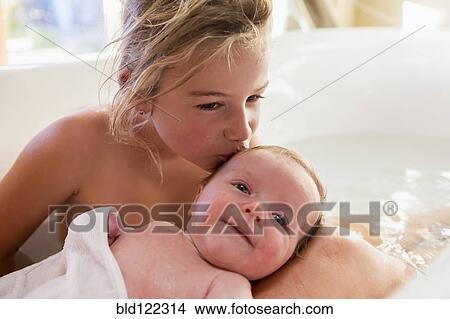 Picture - Caucasian girl kissing newborn baby in bath. Fotosearch
