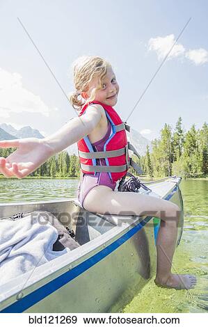 Stock Photo - Caucasian girl sitting on top of canoe on lake. Fotosearch
