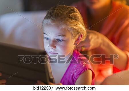 Caucasian girl using digital tablet as mother braids hair View Large Photo Image Stock Photo - Caucasian girl using digital tablet as mother braids hair. Fotosearch