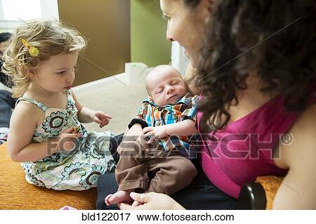 Stock Photo - Caucasian girl watching mother hold newborn boy. Fotosearch