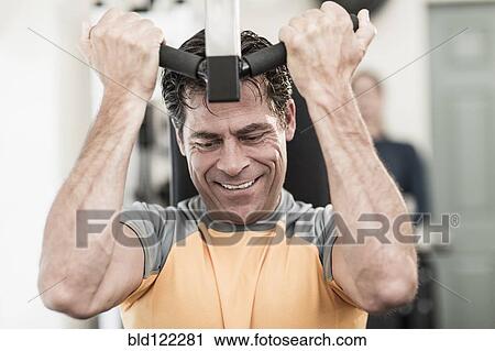 Stock Image - Caucasian man exercising in gym. Fotosearch