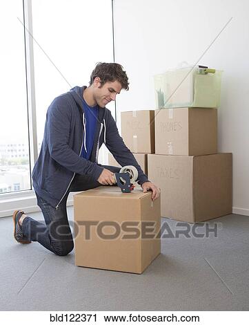 Stock Image - Caucasian man packing cardboard boxes. Fotosearch