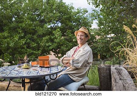 Caucasian man sitting at table outdoors View Large Photo Image Stock Image - Caucasian man sitting at table outdoors. Fotosearch