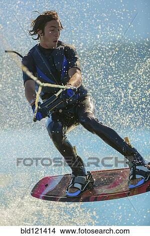 Picture - Caucasian man wakeboarding on lake. Fotosearch