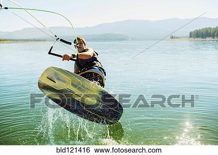 Stock Photograph - Caucasian man wakeboarding on lake. Fotosearch