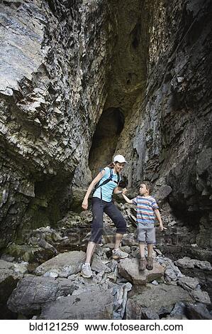 Stock Photo - Caucasian mother and son exploring cave. Fotosearch