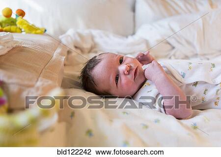 Stock Image - Caucasian newborn baby boy laying on bed. Fotosearch