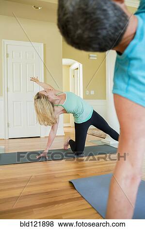 Stock Photo - Caucasian people practicing yoga in home. Fotosearch