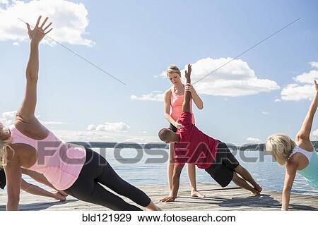 Caucasian people practicing yoga on wooden dock View Large Photo Image Stock Photo - Caucasian people practicing yoga on wooden dock. Fotosearch