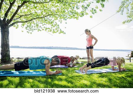 Stock Photo - Caucasian people practicing yoga outdoors. Fotosearch