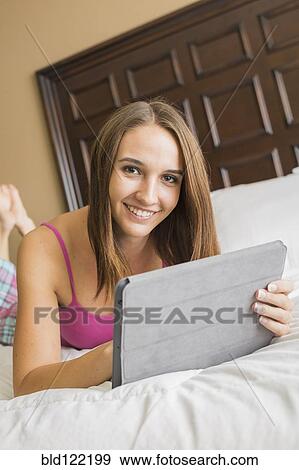Stock Photo - Caucasian woman using digital tablet in bed. Fotosearch