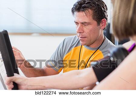 Picture - Caucasian woman working with personal trainer in gym. Fotosearch