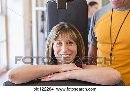 Picture - Caucasian woman working with personal trainer in gym. Fotosearch