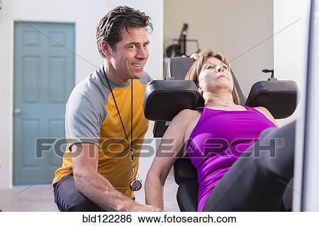 Stock Photograph - Caucasian woman working with personal trainer in gym. Fotosearch