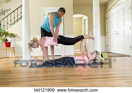 Stock Photo - Caucasian women practicing acroyoga in home. Fotosearch