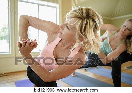Stock Image - Caucasian women practicing yoga in class. Fotosearch