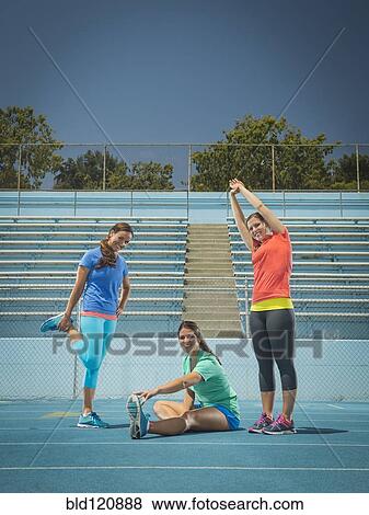 Stock Photo - Caucasian women stretching on running track. Fotosearch