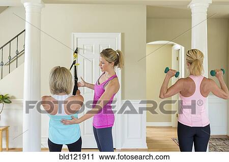 Stock Image - Caucasian women working with trainer in home. Fotosearch