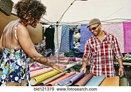 Couple browsing fabrics at flea market View Large Photo Image Stock Photo - Couple browsing fabrics at flea market. Fotosearch