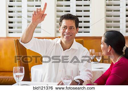 Stock Photograph - Couple calling waiter at restaurant. Fotosearch