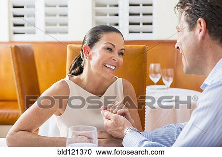 Stock Image - Couple sitting together in restaurant. Fotosearch