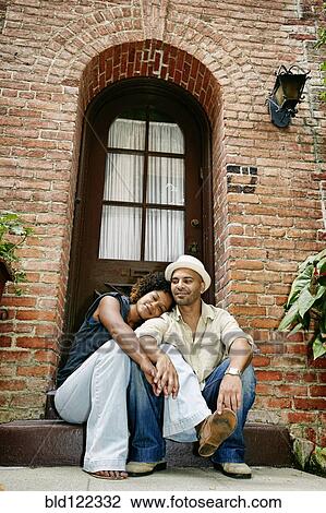 Stock Image - Couple smiling together on front stoop. Fotosearch