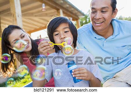 Family blowing bubbles outdoors View Large Photo Image Stock Image - Family blowing bubbles outdoors. Fotosearch