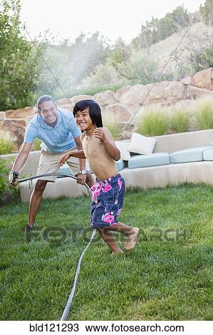Father and son playing with hose in backyard View Large Photo Image Stock Image - Father and son playing with hose in backyard. Fotosearch