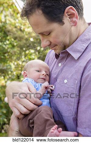 Picture - Father holding newborn son outdoors. Fotosearch