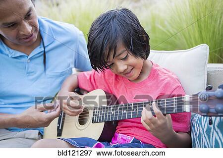 Stock Photo - Father teaching son to play guitar outdoors. Fotosearch