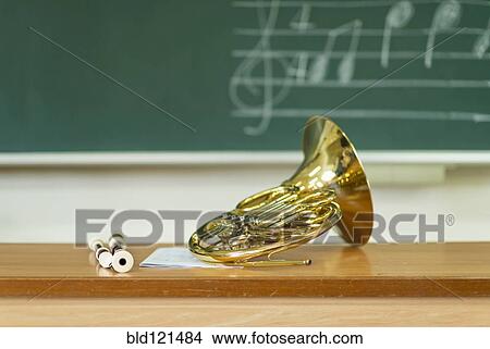 Picture - French horn sitting on desk in classroom. Fotosearch