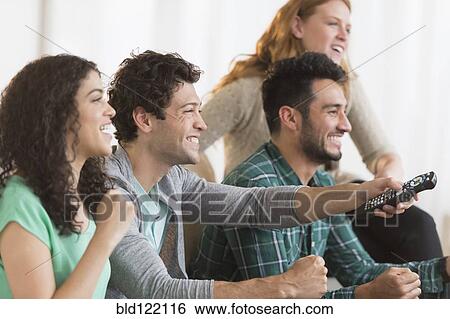 Friends watching television together on sofa View Large Photo Image Stock Photograph - Friends watching television together on sofa. Fotosearch