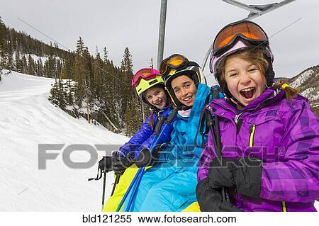 Stock Photography - Girls riding ski lift on snowy slope. Fotosearch