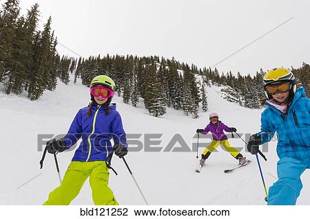 Stock Image - Girls skiing together on snowy slope. Fotosearch