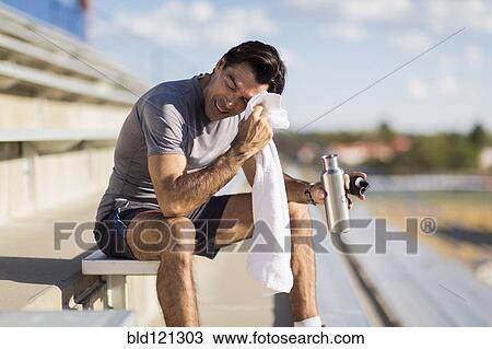 Stock Image - Hispanic athlete resting on bleachers. Fotosearch