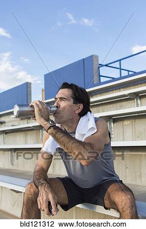 Stock Image - Hispanic athlete resting on bleachers. Fotosearch