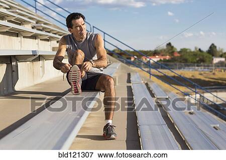 Stock Photo - Hispanic athlete resting on bleachers. Fotosearch