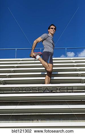 Hispanic athlete stretching on bleachers View Large Photo Image Stock Image - Hispanic athlete stretching on bleachers. Fotosearch