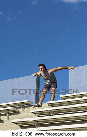 Stock Photo - Hispanic athlete stretching on bleachers. Fotosearch