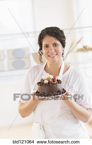Hispanic baker holding chocolate cake View Large Photo Image Picture - Hispanic baker holding chocolate cake. Fotosearch