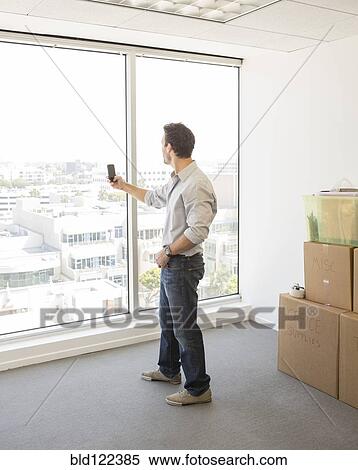 Stock Photography - Hispanic businessman taking photograph in new office. Fotosearch
