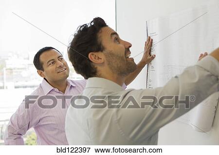 Hispanic businessmen examining blueprints in office View Large Photo Image Stock Photo - Hispanic businessmen examining blueprints in office. Fotosearch