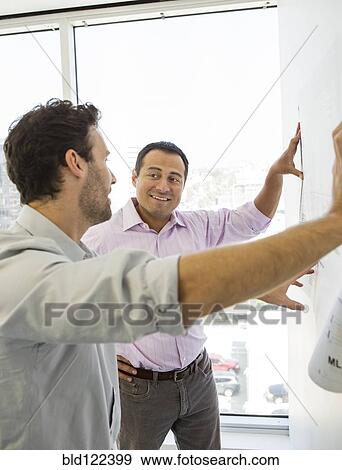 Hispanic businessmen examining blueprints in office View Large Photo Image Stock Photo - Hispanic businessmen examining blueprints in office. Fotosearch