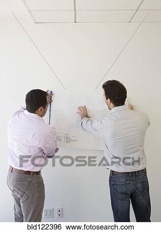 Hispanic businessmen examining blueprints in office View Large Photo Image Stock Photograph - Hispanic businessmen examining blueprints in office. Fotosearch