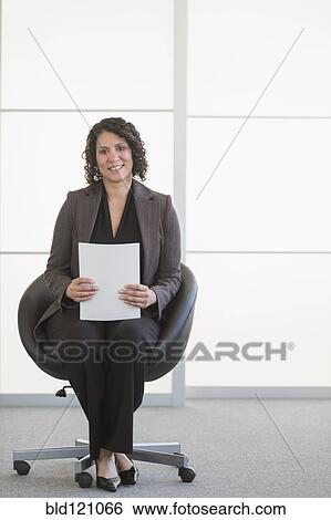 Stock Photograph - Hispanic businesswoman sitting in office chair. Fotosearch