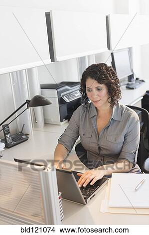 Picture - Hispanic businesswoman working in office. Fotosearch